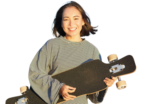 Woman smiling, holding a skateboard, wearing a black and white striped shirt.