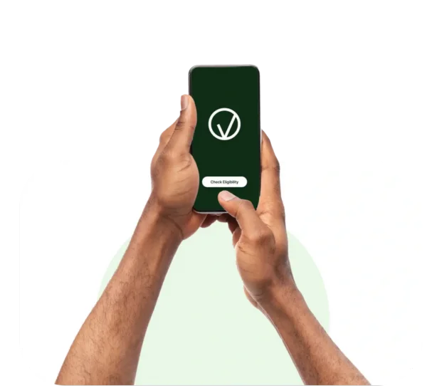 Person holding a smartphone displaying a green screen with a white logo, and a button labeled "Check Eligibility.